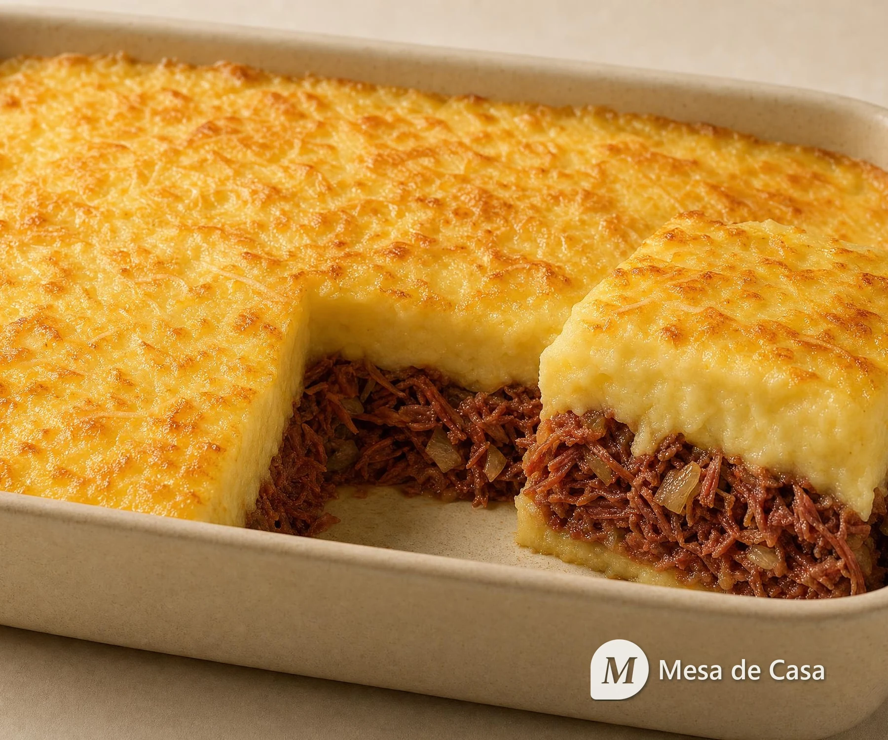 Escondidinho de mandioca dourado com camada aparente de carne-seca desfiada