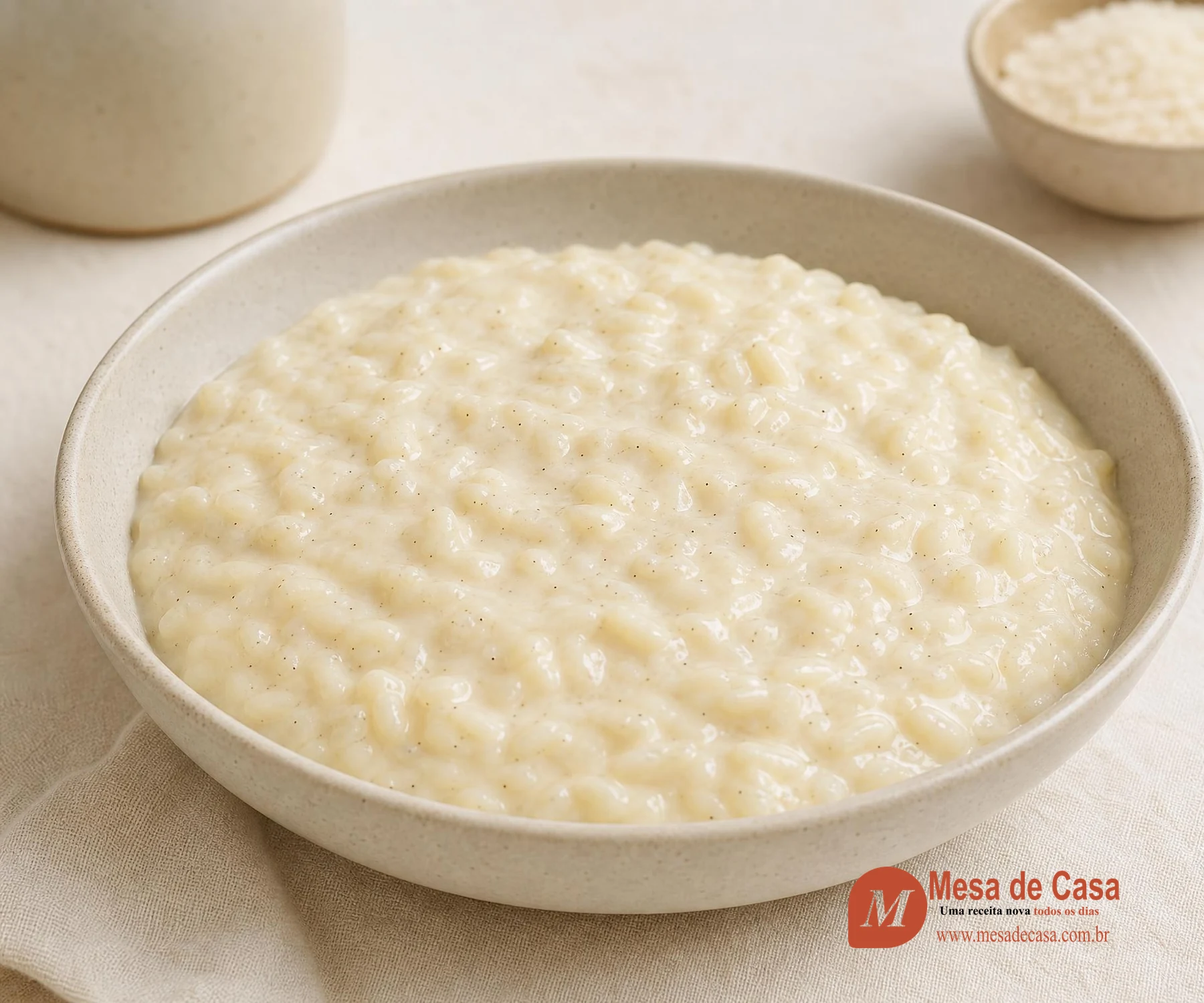 Arroz-doce cremoso de cor marfim com pontos de baunilha em tigela clara