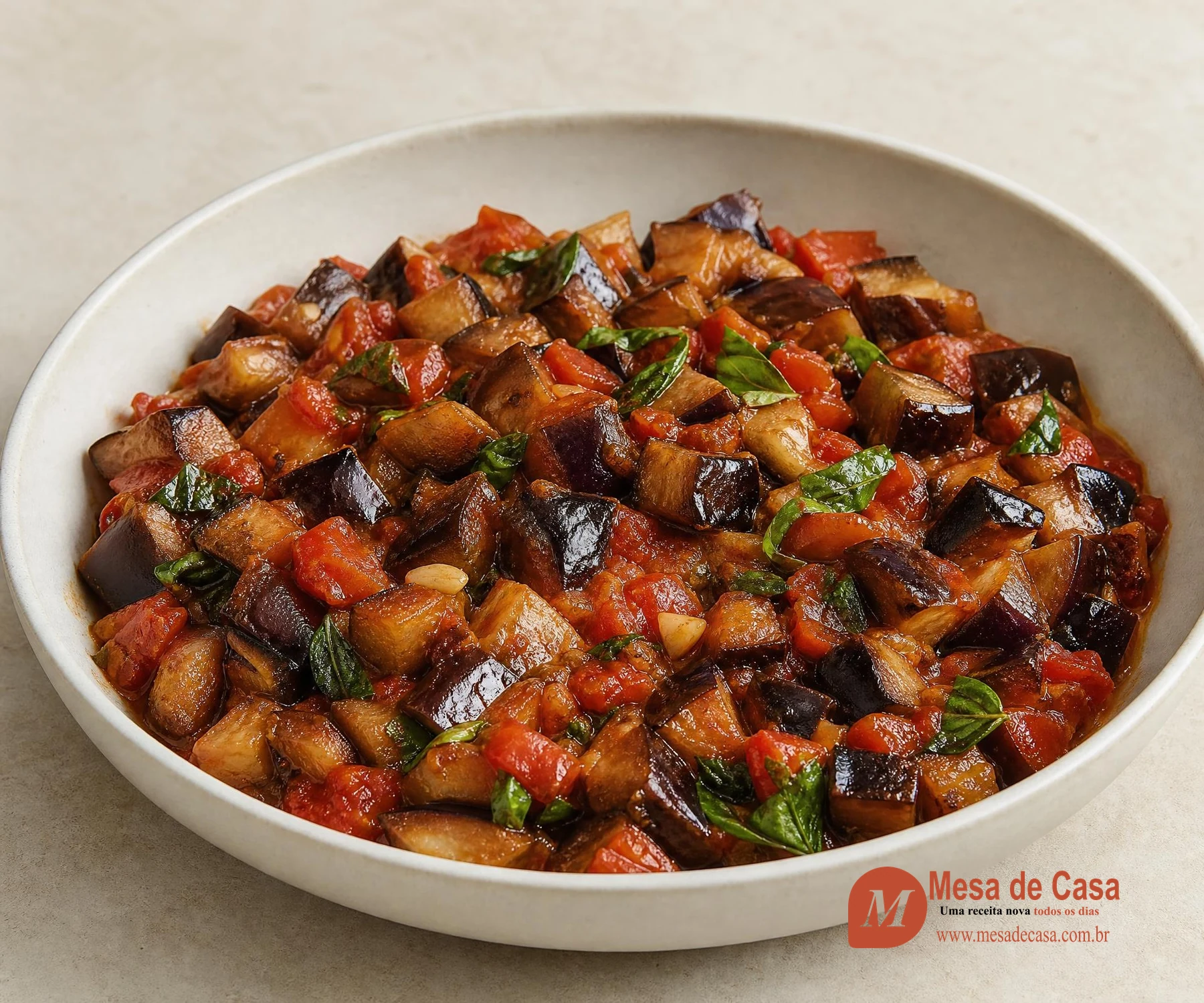 Cubos dourados de berinjela com tomate, alho e manjericão em tigela clara