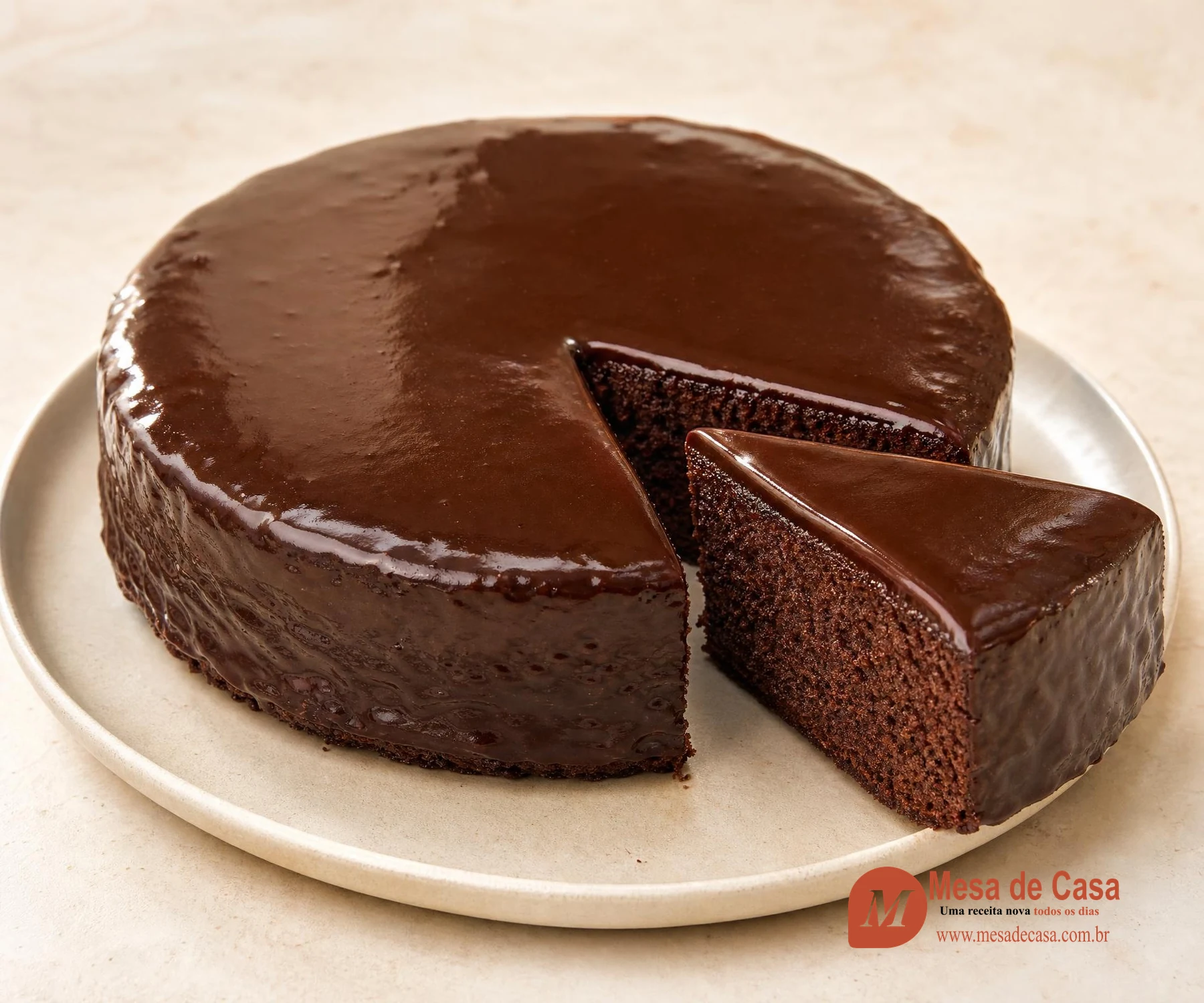 Bolo redondo de chocolate com calda escura e uma fatia cortada em prato claro