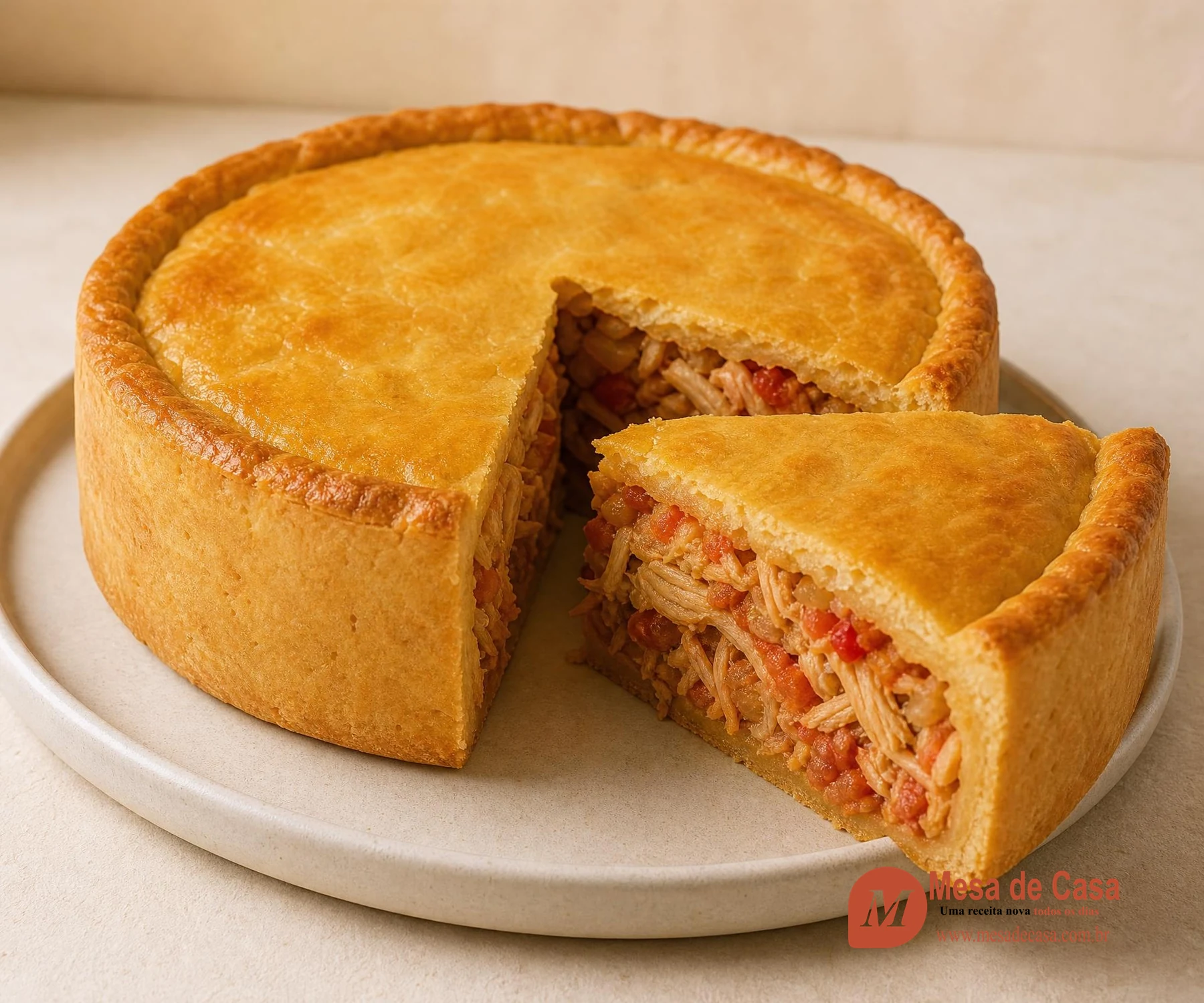 Empadão dourado com fatia cortada e recheio de frango desfiado com tomate