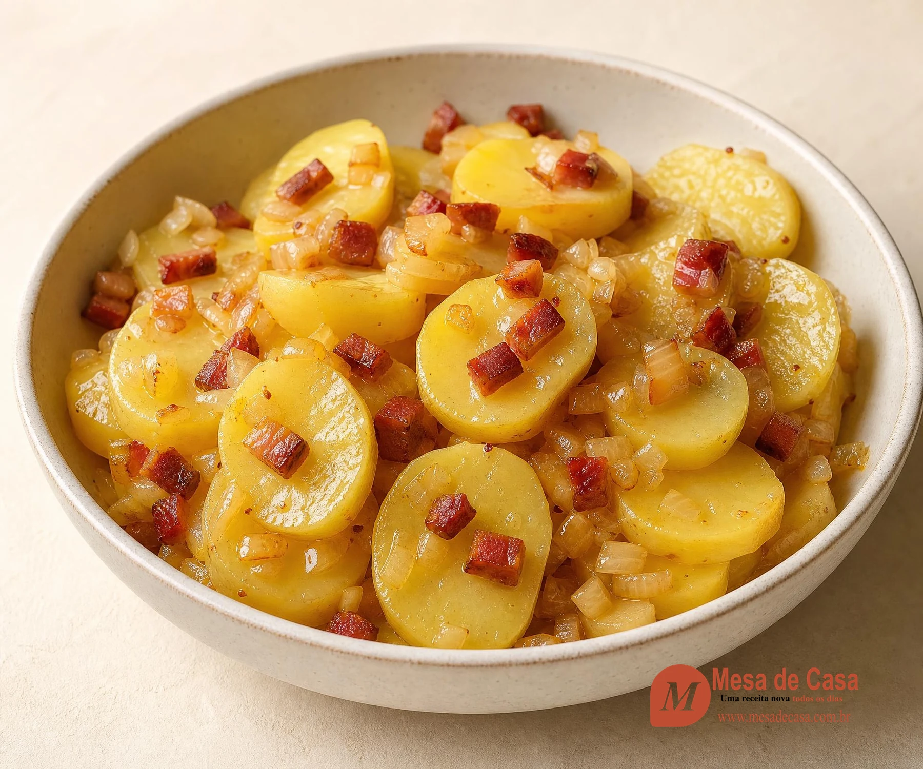 Salada morna de rodelas de batata com bacon dourado e cebola em tigela clara