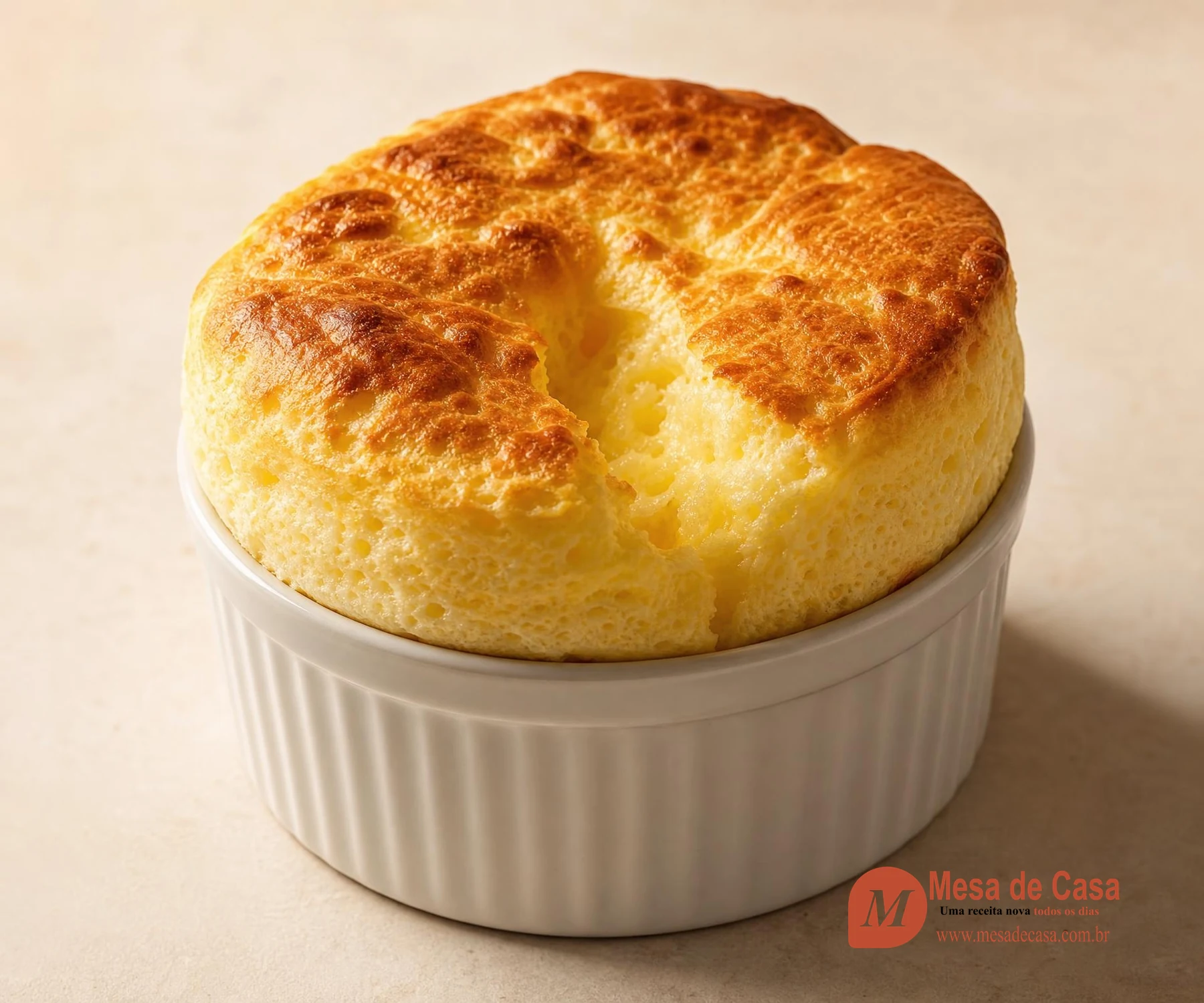 Suflê de queijo alto e dourado acima da borda de um ramequim claro